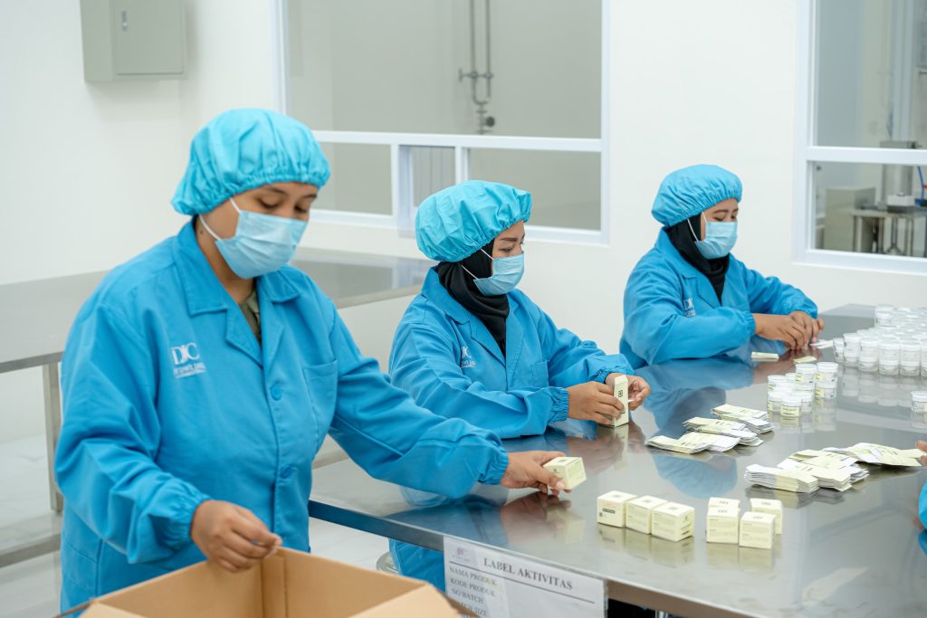 The packing team in blue uniforms on the production line — Company Profile, PT Dwi Jaya Cosmedika