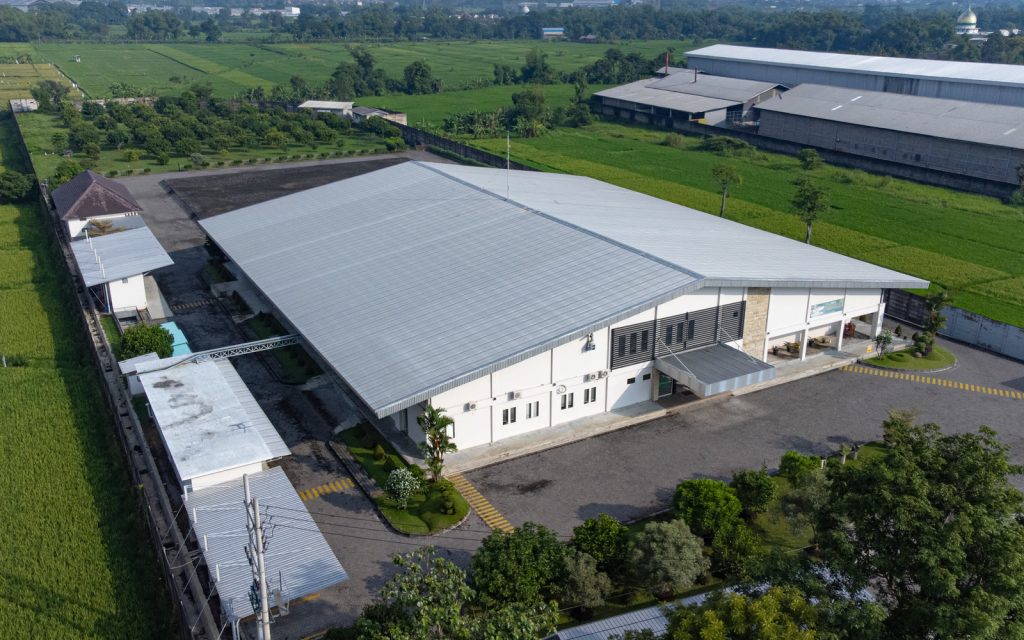 Aerial of the factory and rice fields, a calm landscape without faces — Company Profile, PT Estetika Semesta Raya (Eksotika)